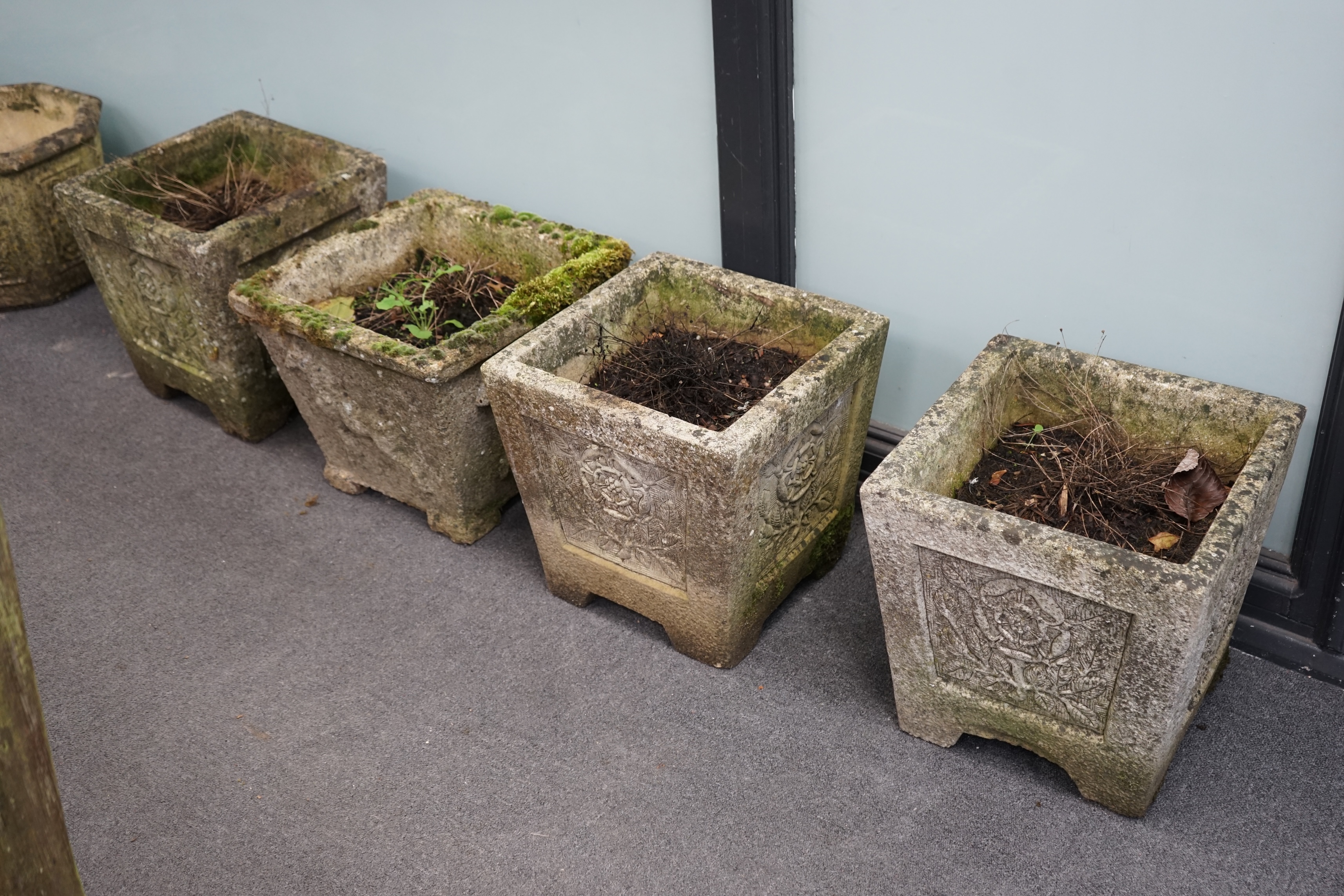 A set of three reconstituted stone garden planters, decorated with Tudor roses, 36cm sq., 37cm high, and a single square planter moulded in relief with a horse